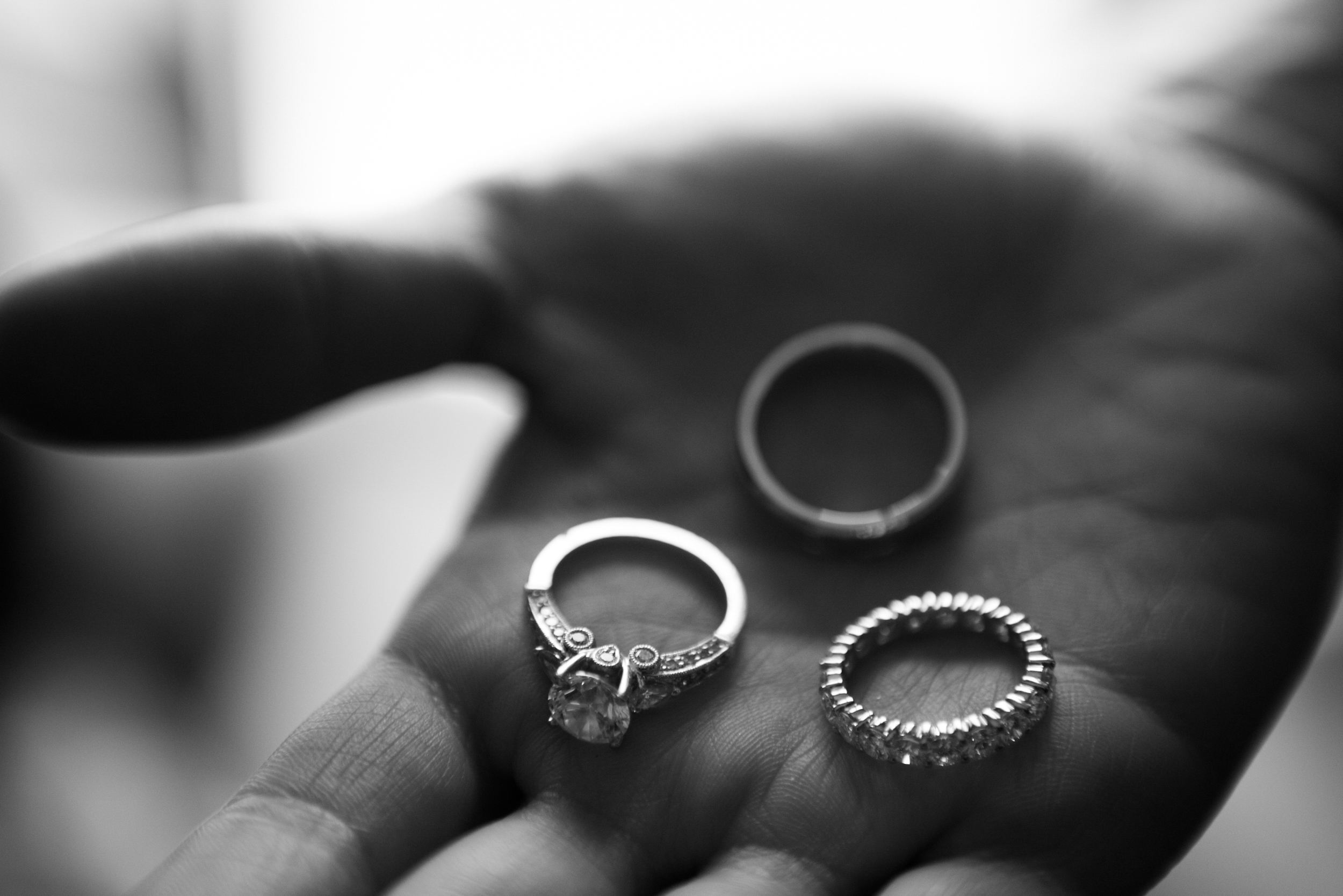 Close-up of three rings held on a hand in black and white.