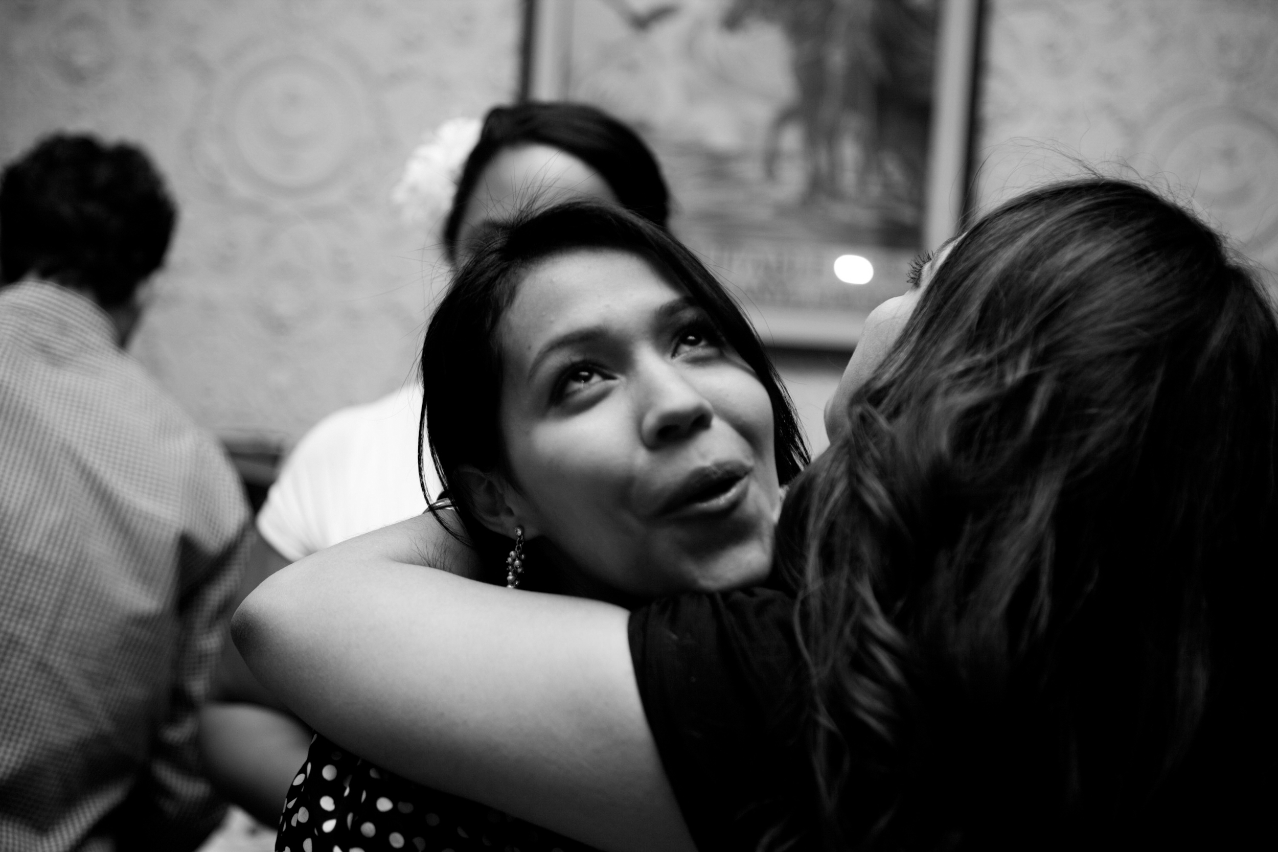 Black and white photo of a woman looking upwards while hugging someone.