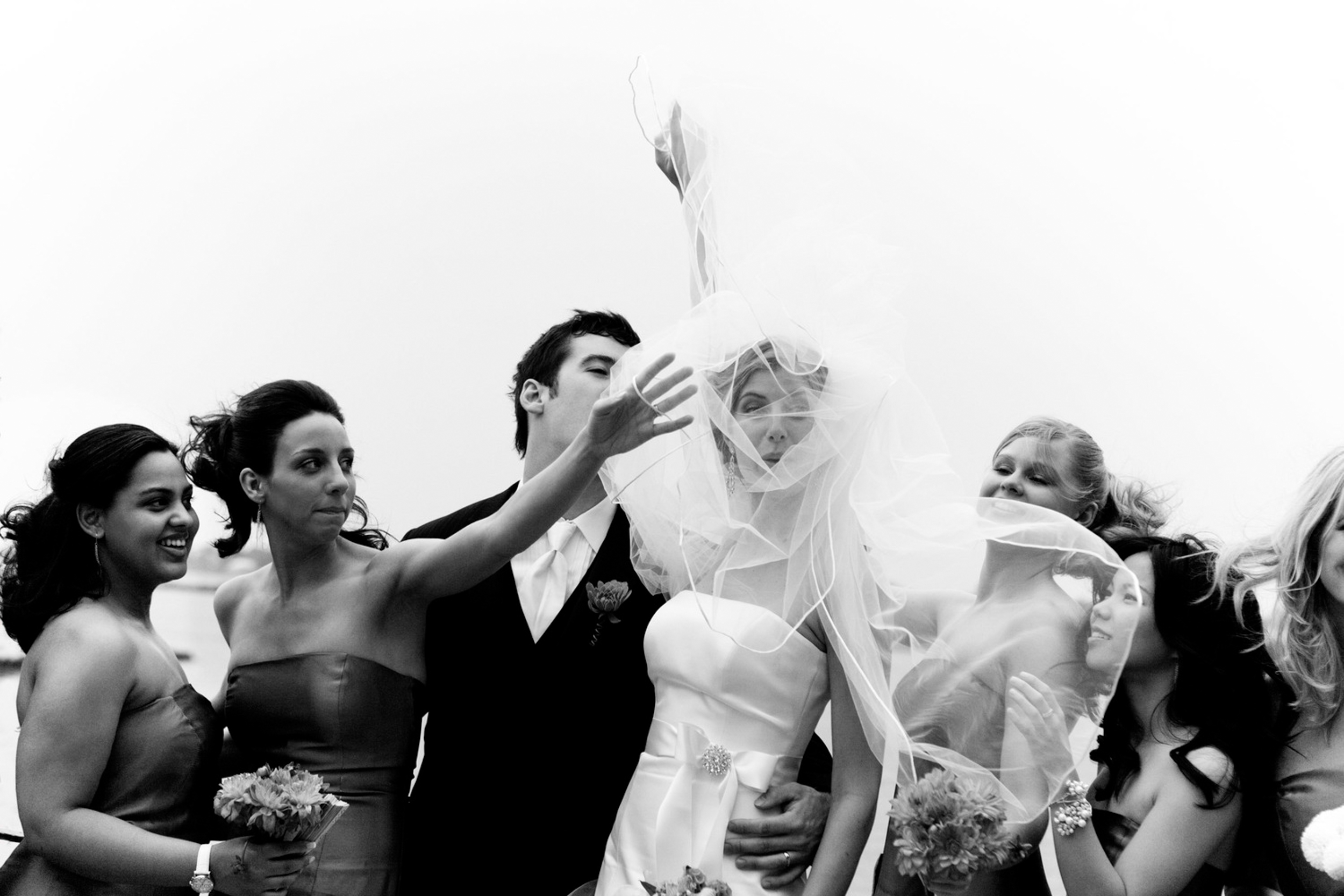 Bride joyfully tossing bouquet with bridesmaids eagerly reaching for it.