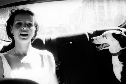 Black and white photo of a smiling person in a car.