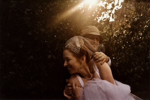 A couple shares a joyful moment in warm sunlight and nature.