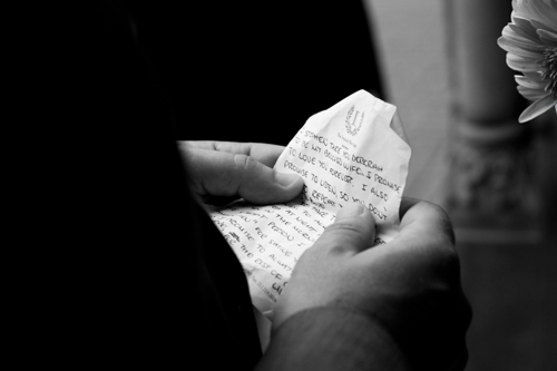 Hands holding a crumpled handwritten note.