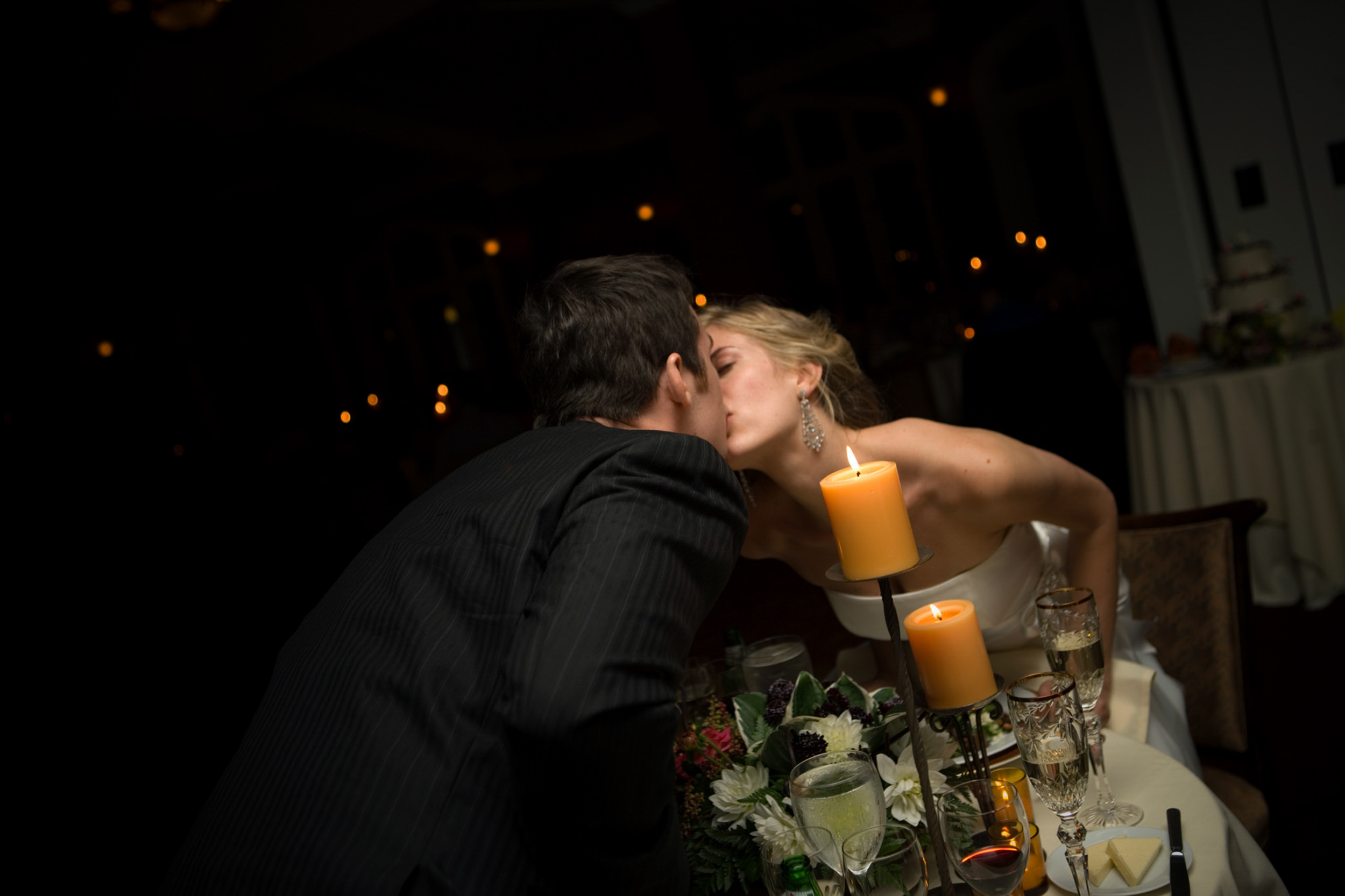 Couple sharing a candlelit kiss at a romantic dinner.