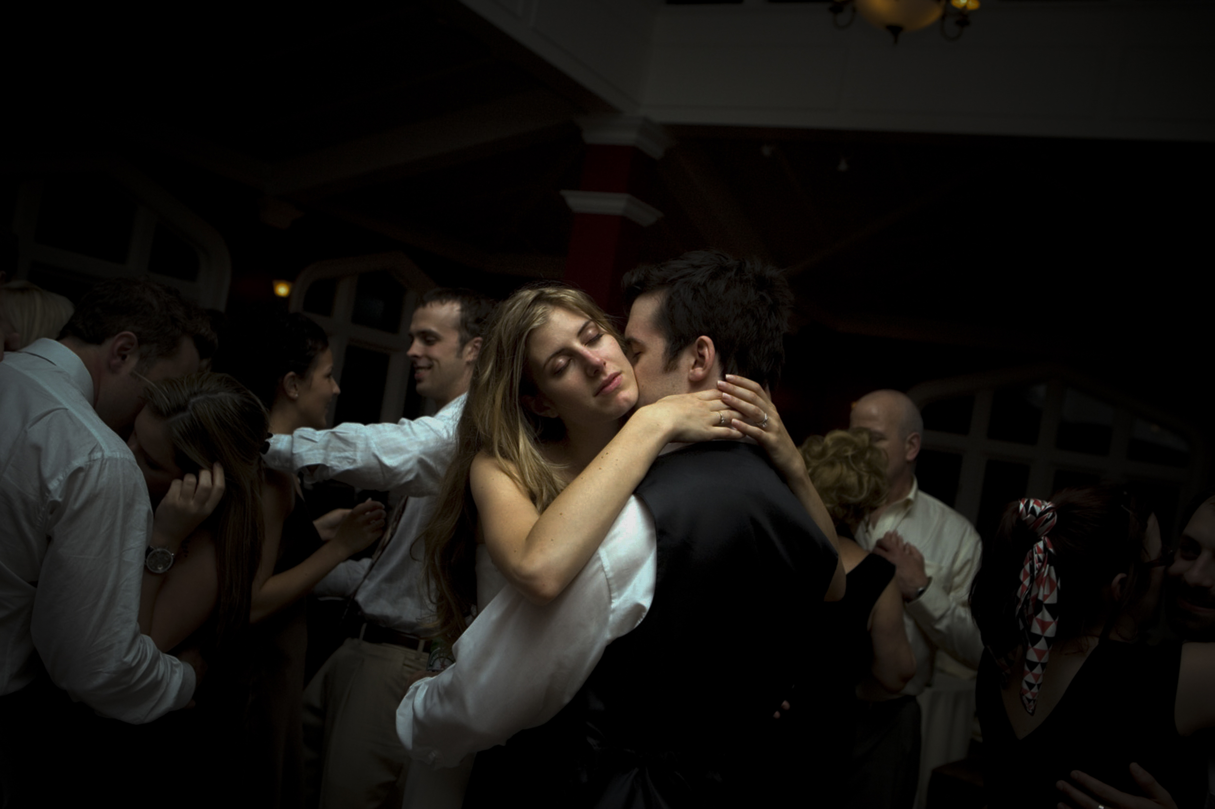 Couple embracing on the dance floor in a dimly lit room.