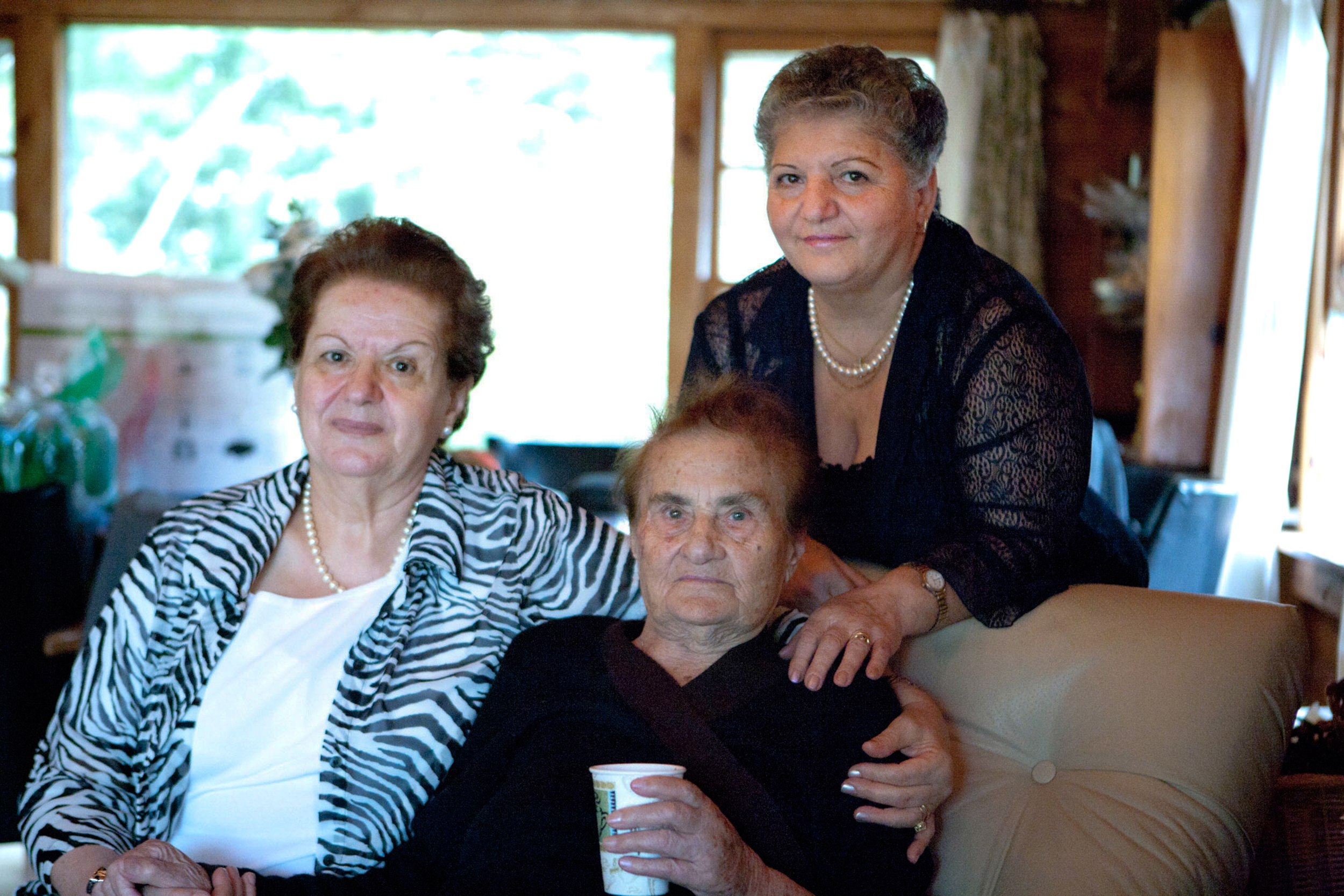 Three adults posing together on a couch indoors.