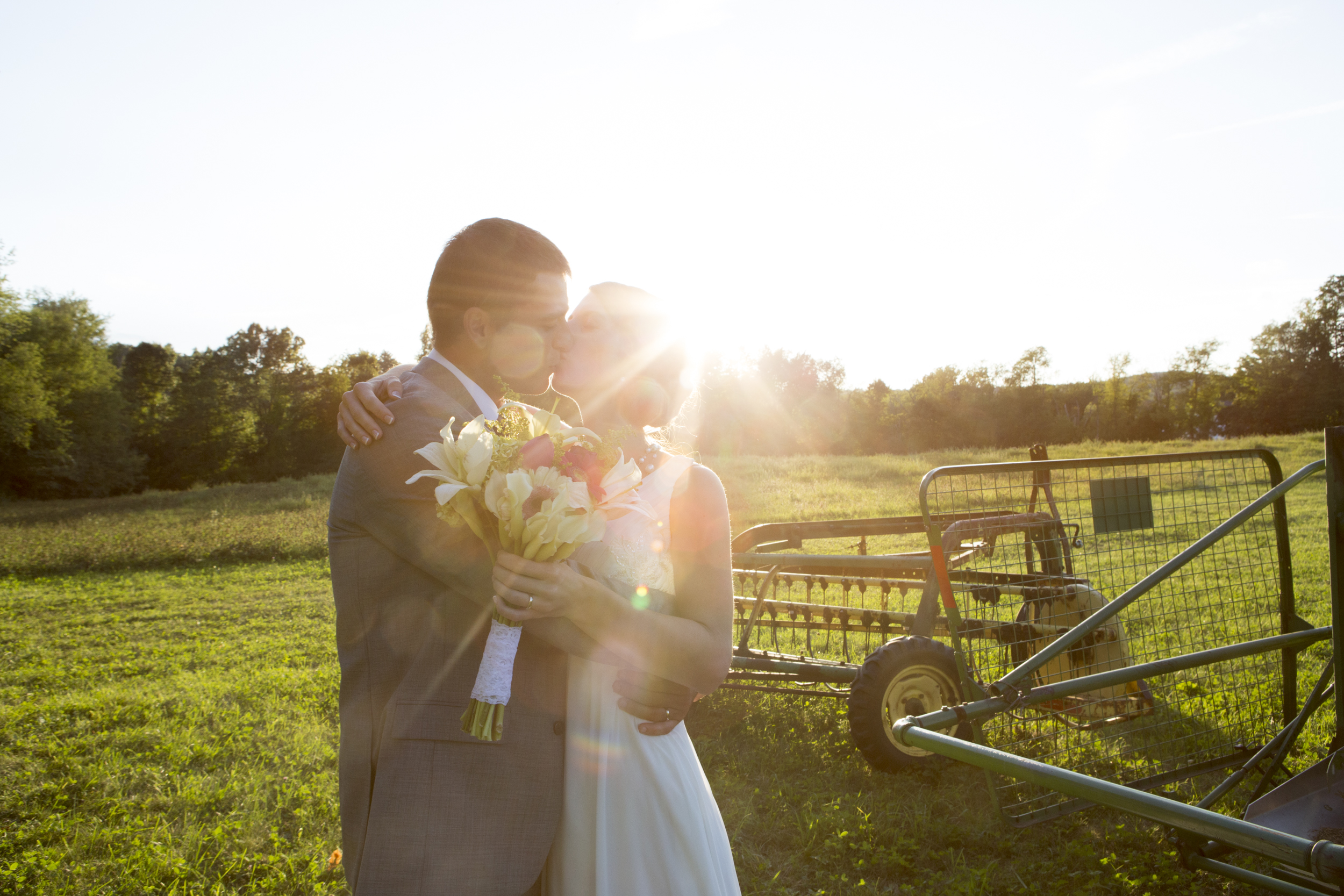 Couple sharing a kiss during a sunset wedding outdoors.