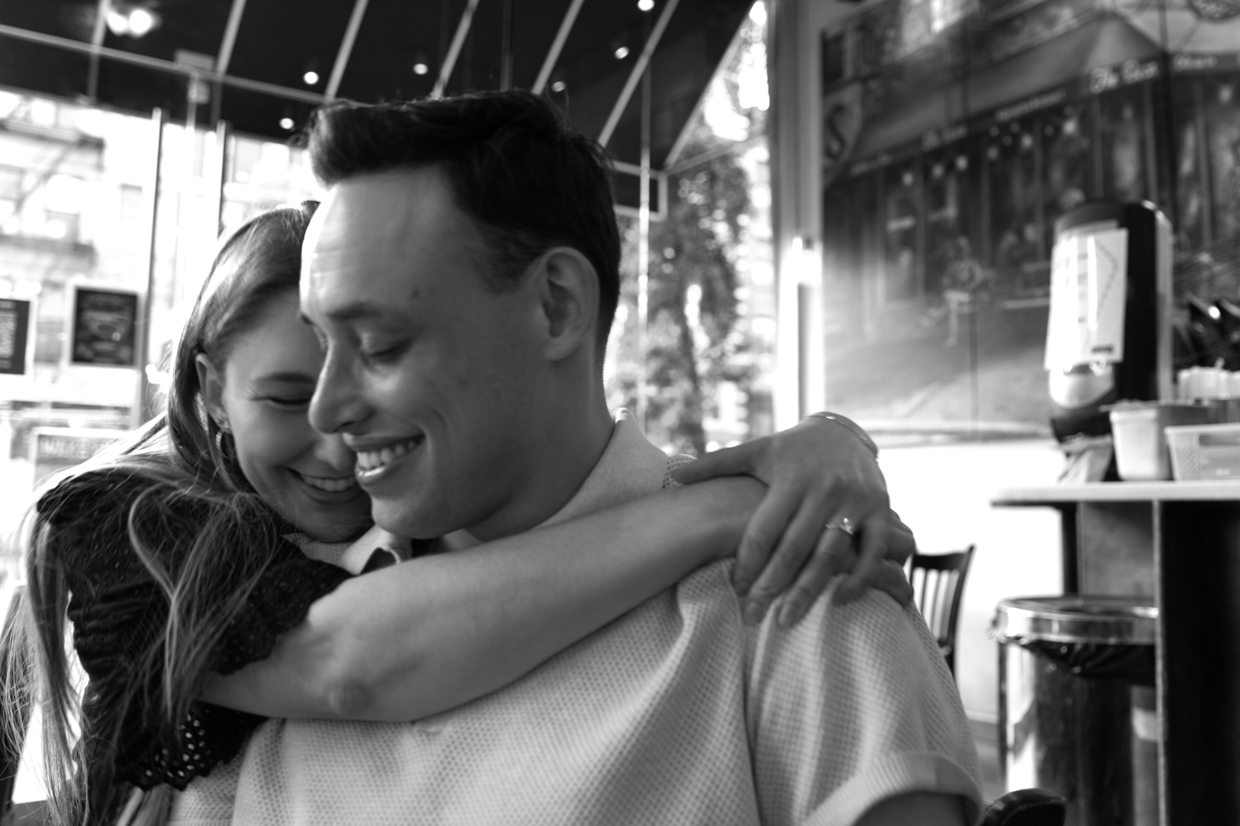 Black and white photo of a smiling couple embracing indoors.